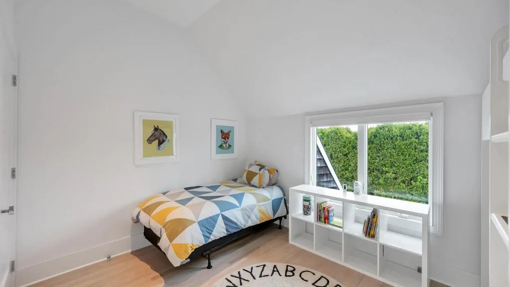 A bright bedroom with a single bed beside a large window.
