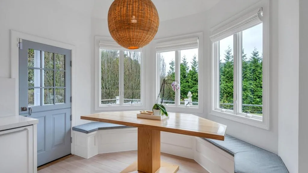 A bright dining nook has a curved bench beneath large windows.