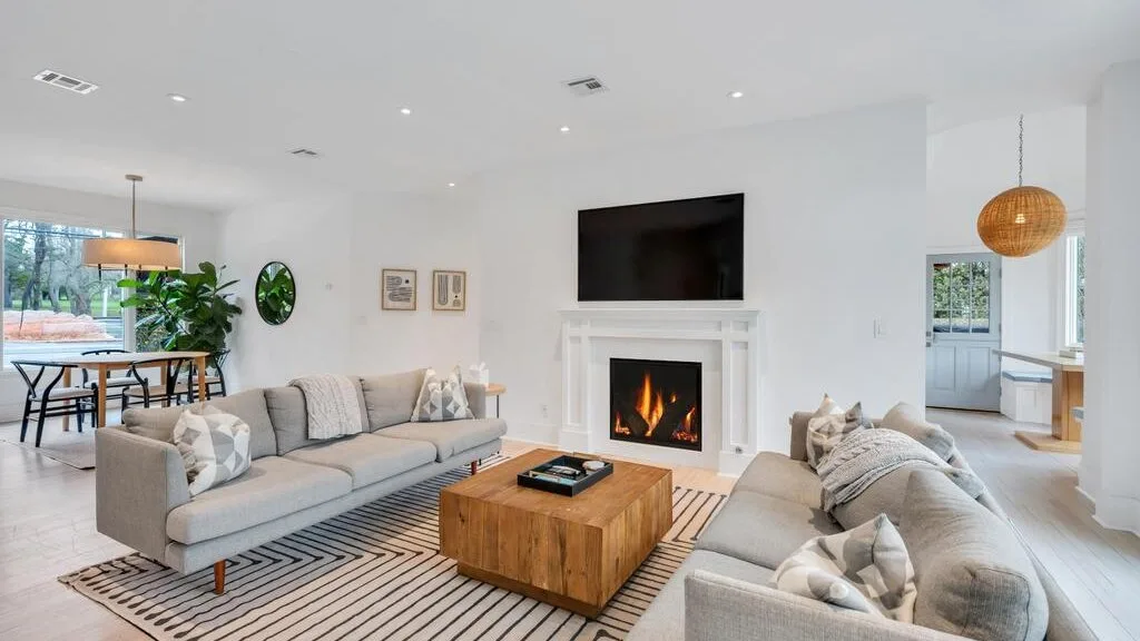 Living room with seating arranged around a fireplace and television.
