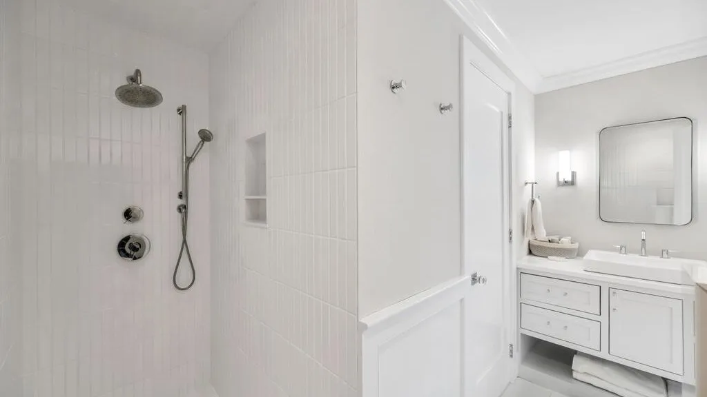 A bright bathroom with a tiled shower and a vanity with a mirror.