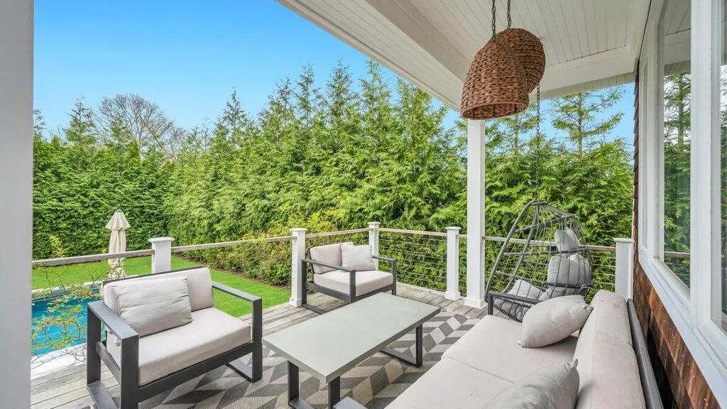 A covered outdoor seating area overlooks a garden and swimming pool.