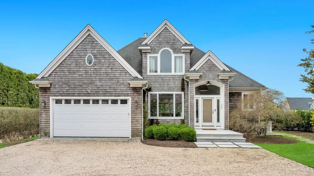 A large house with gray shingle siding, white trim, and an attached garage.
