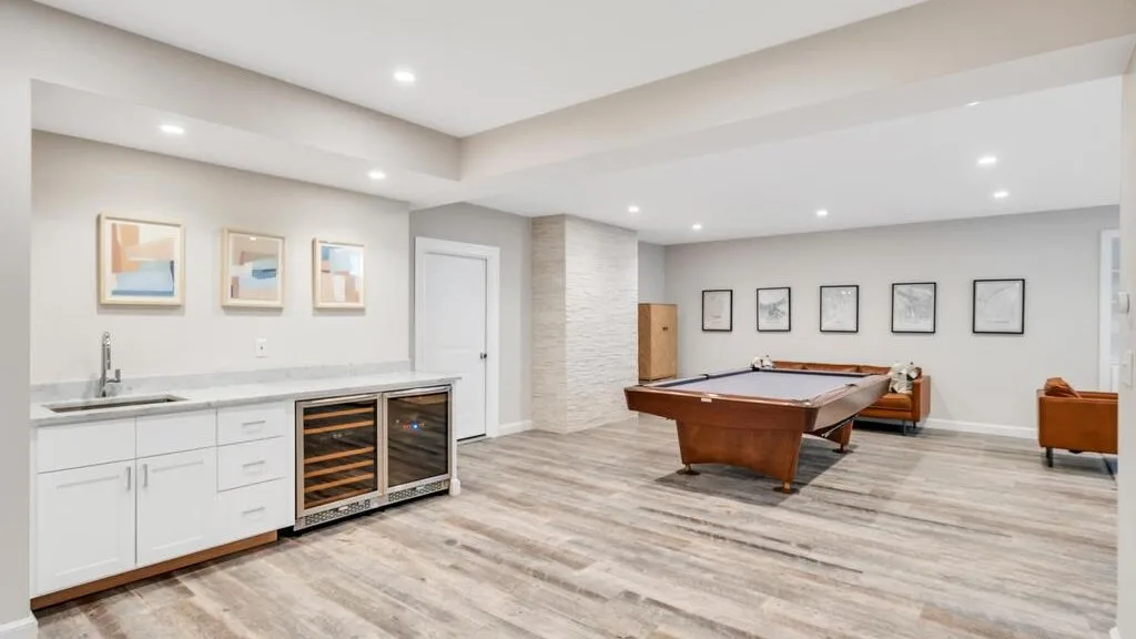 A bright recreation room with a pool table and a built-in beverage refrigerator.