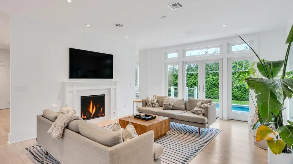 A bright living room with seating arranged around a fireplace and coffee table.