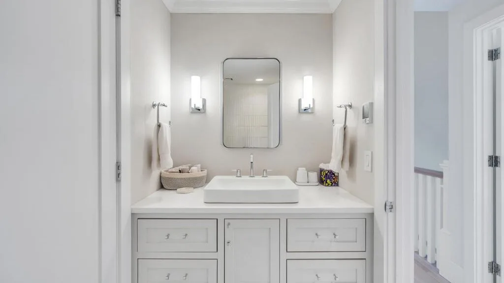 A bright bathroom vanity with a sink, mirror, and wall lights.