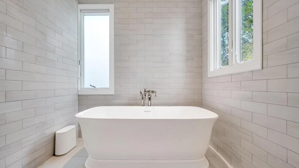 A bright bathroom with a freestanding bathtub and windows.
