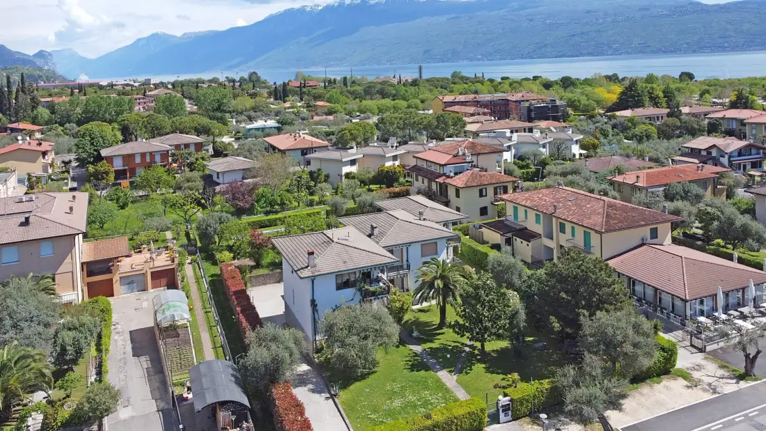 Vista aérea de un barrio residencial con un lago y montañas a lo lejos.