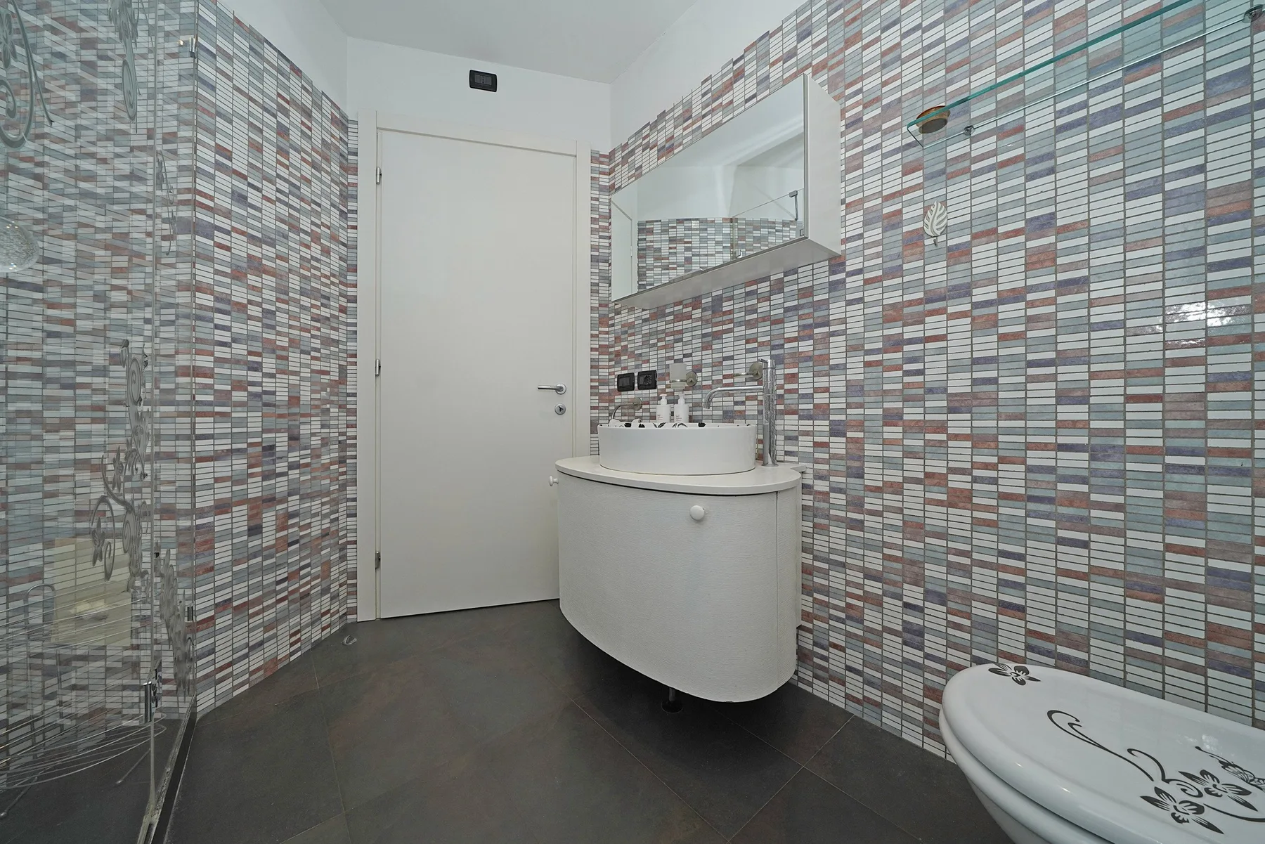Un baño con azulejos, lavabo, espejo e inodoro.