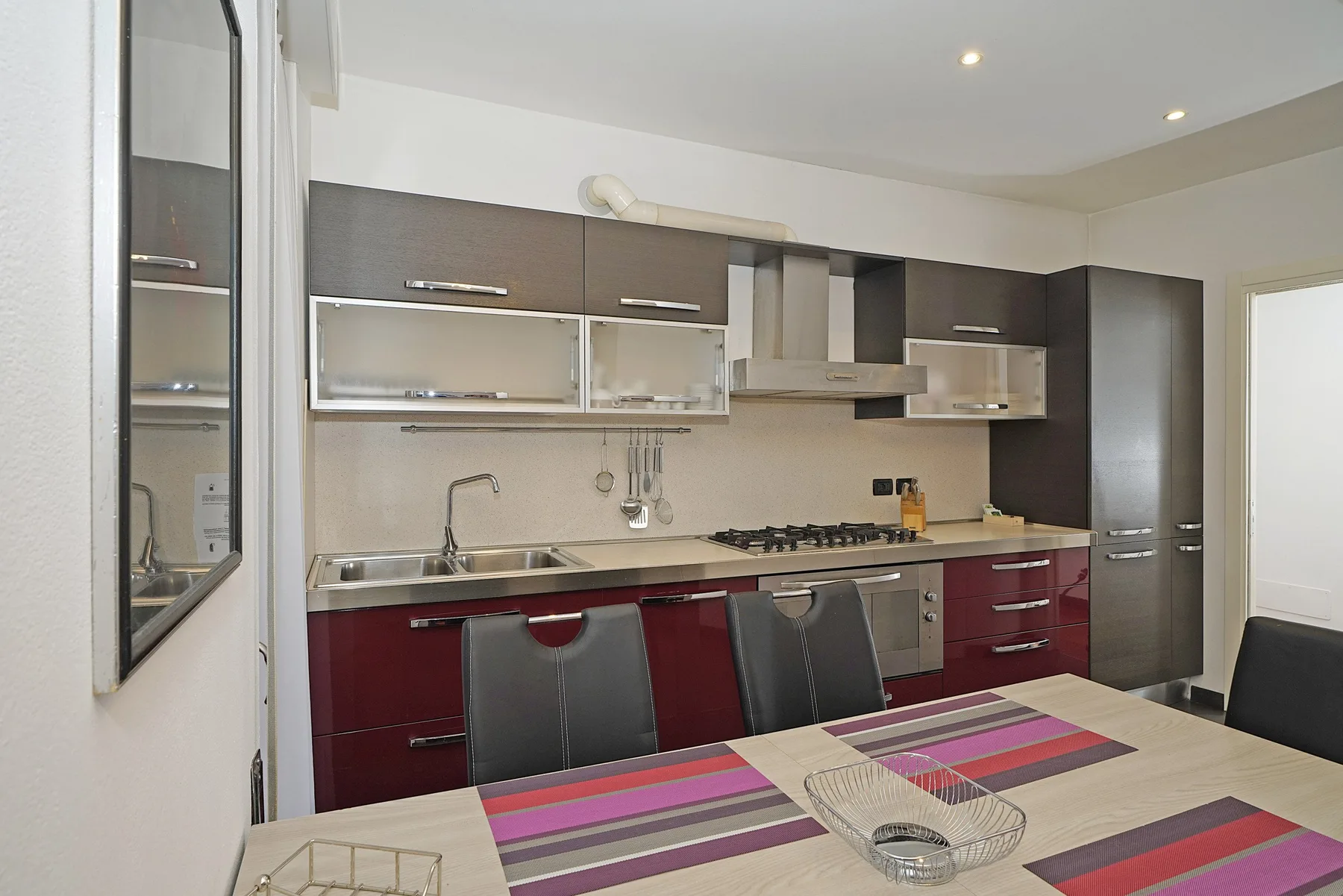 Una cocina moderna con gabinetes oscuros, una estufa de gas y una mesa de comedor.