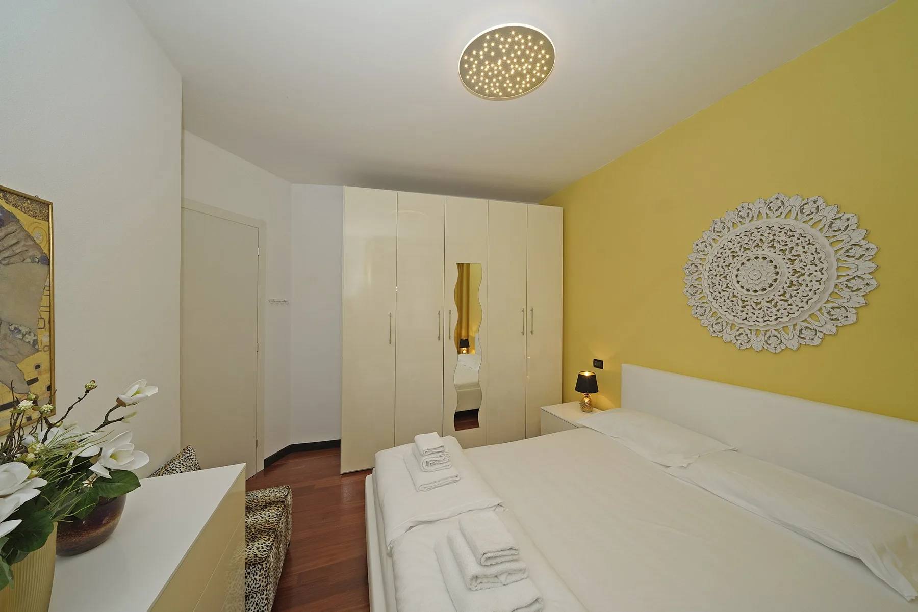 Un dormitorio con una cama, un armario blanco y una pared amarilla.