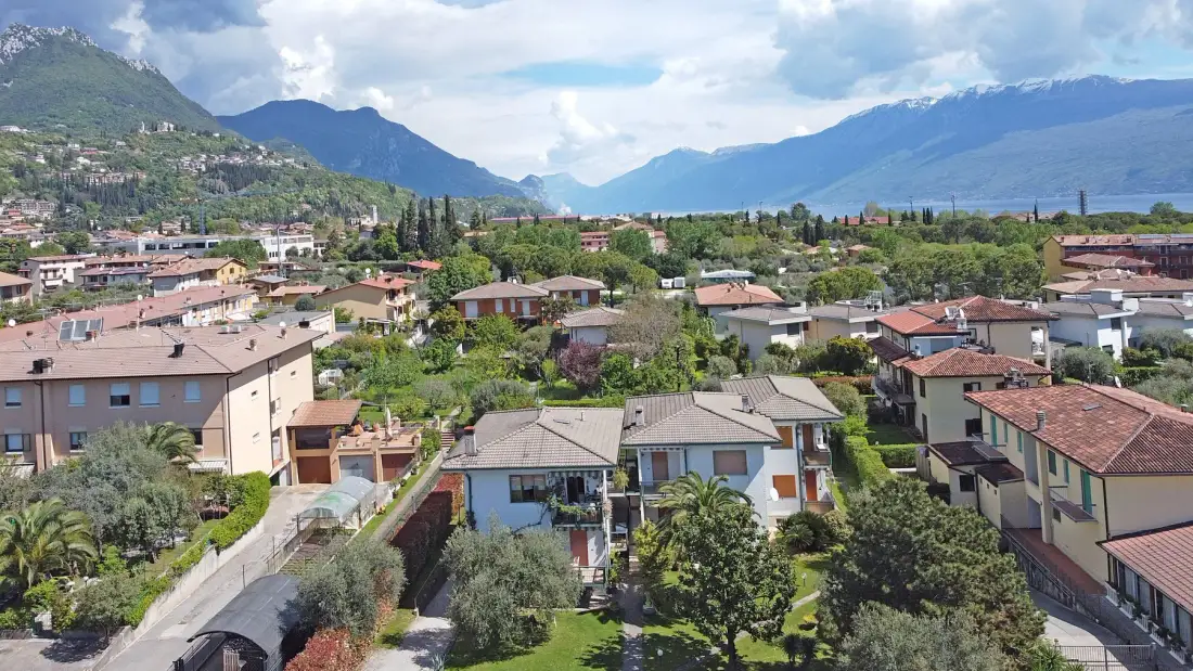 Un barrio residencial entre árboles verdes, con montañas a lo lejos.