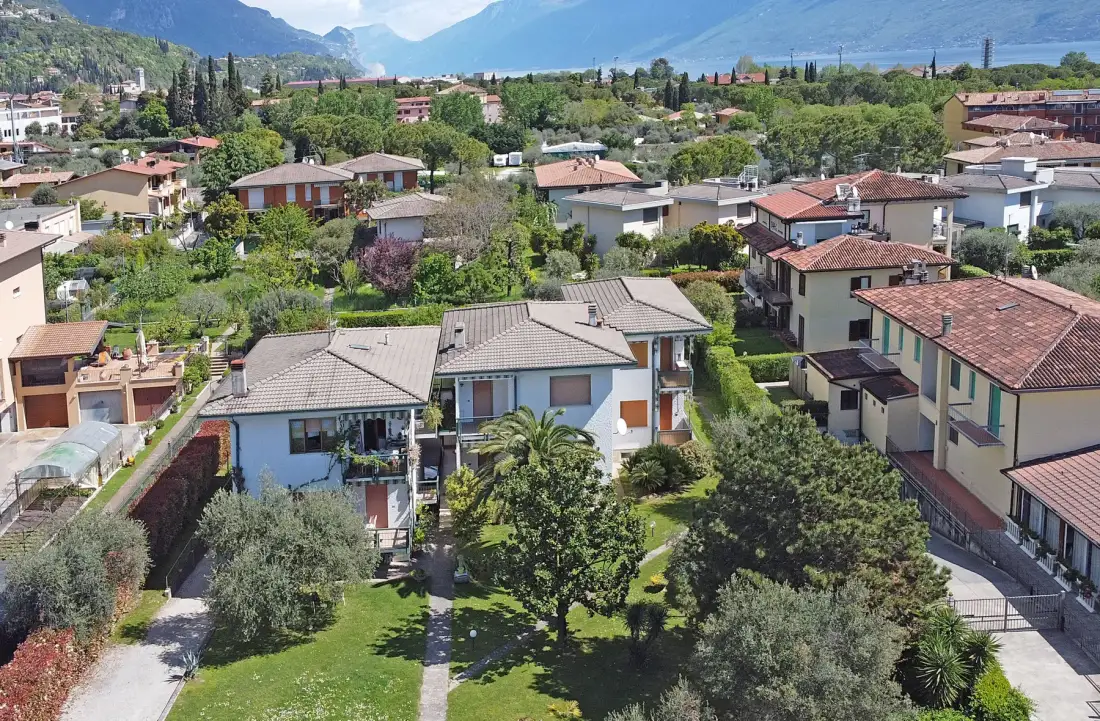 Vista aérea de un barrio residencial con casas, jardines y montañas a lo lejos.