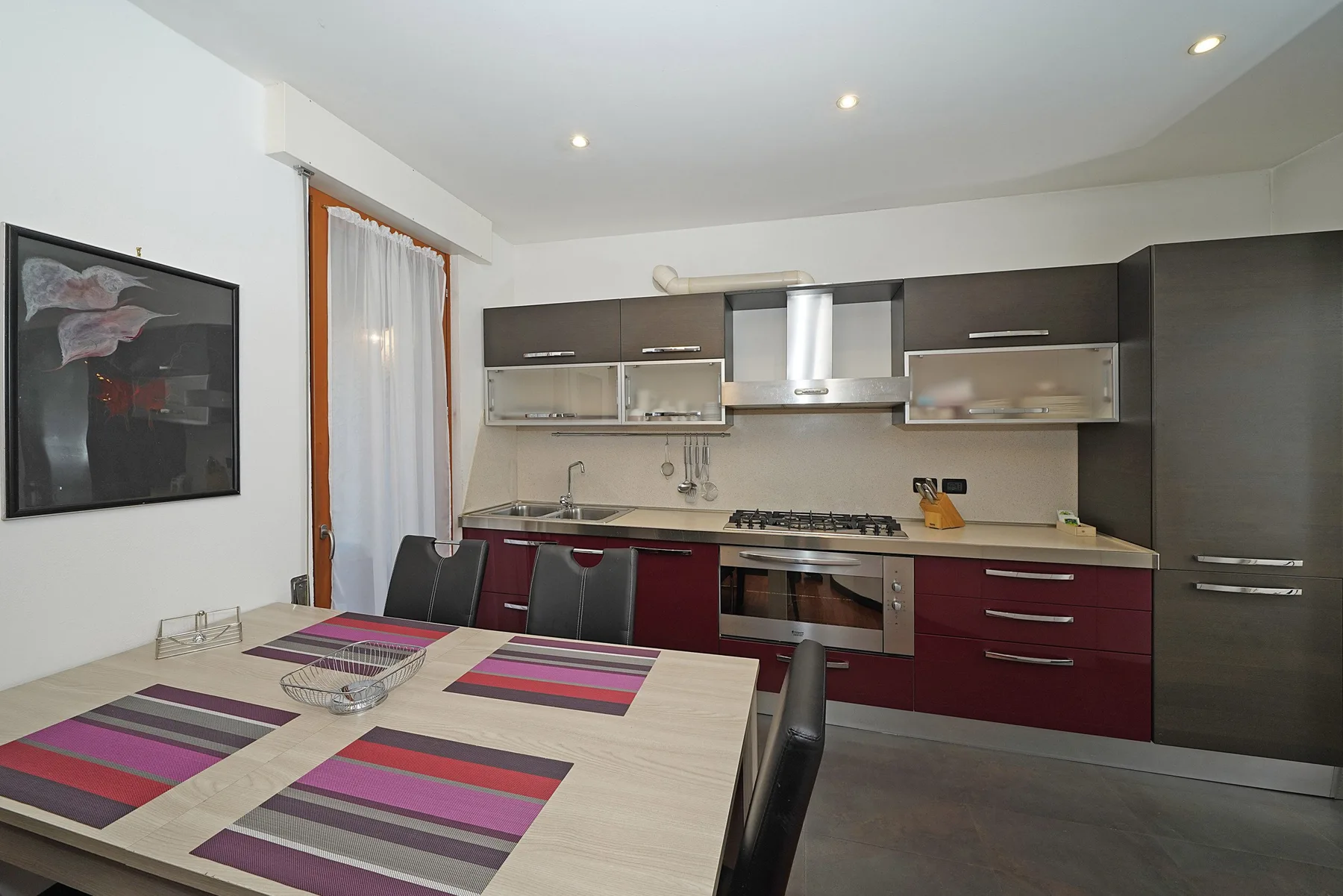 Una cocina y comedor con una mesa frente a los armarios.