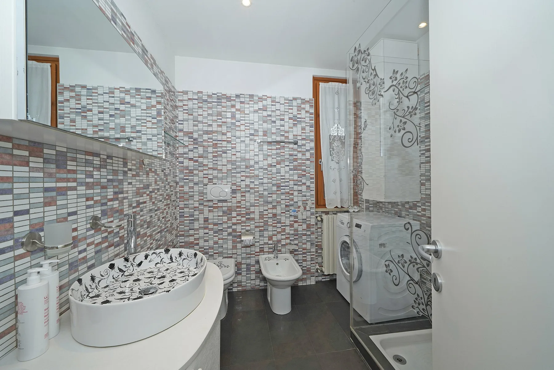 Un baño revestido de azulejos con lavabo, inodoro y ducha.