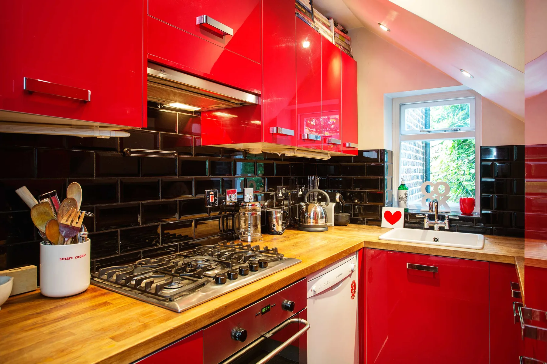 Una cocina luminosa con gabinetes rojos, una placa de cocina y una ventana.
