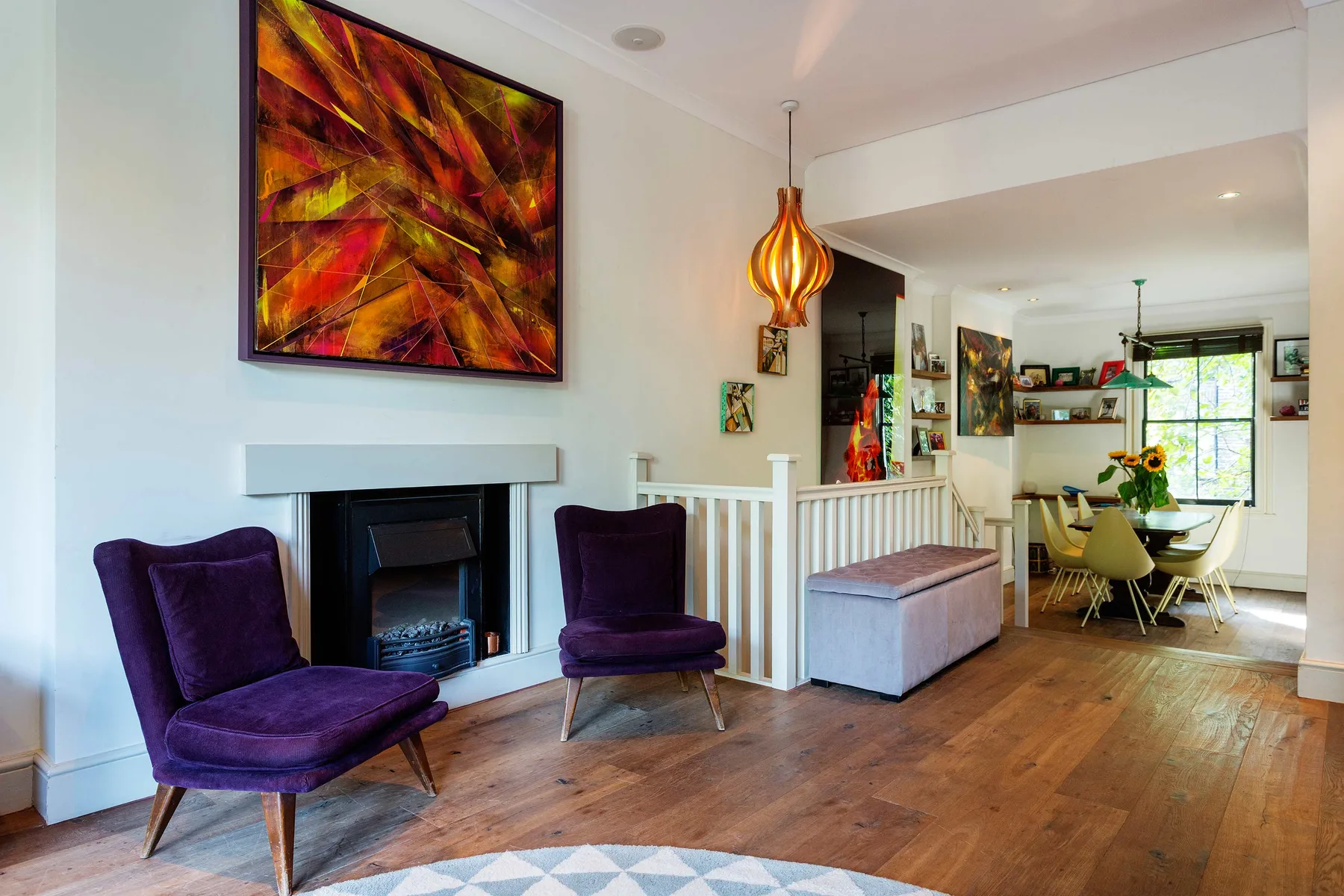 Una sala luminosa con asientos morados, una chimenea y un comedor contiguo.