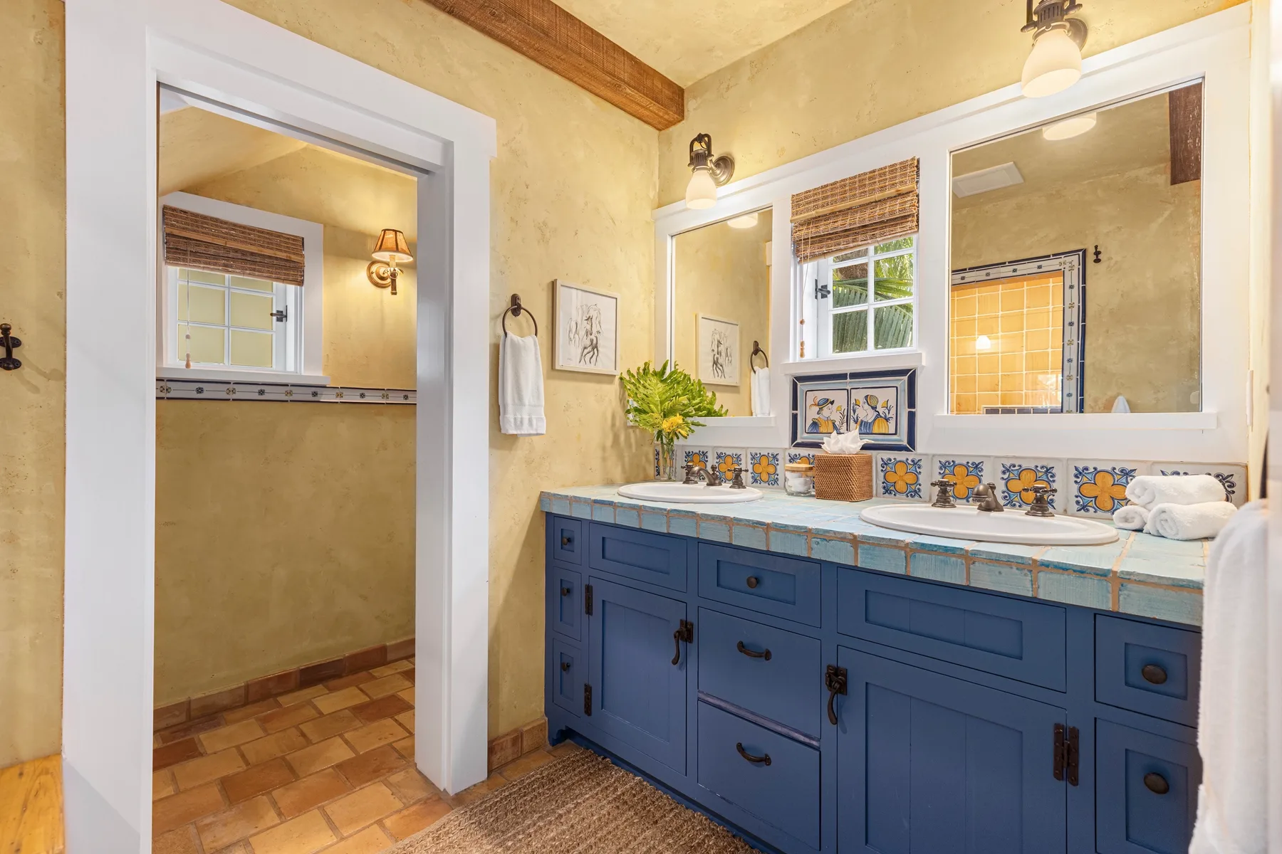 A bathroom vanity with blue cabinetry, twin sinks, and a large wall mirror.
