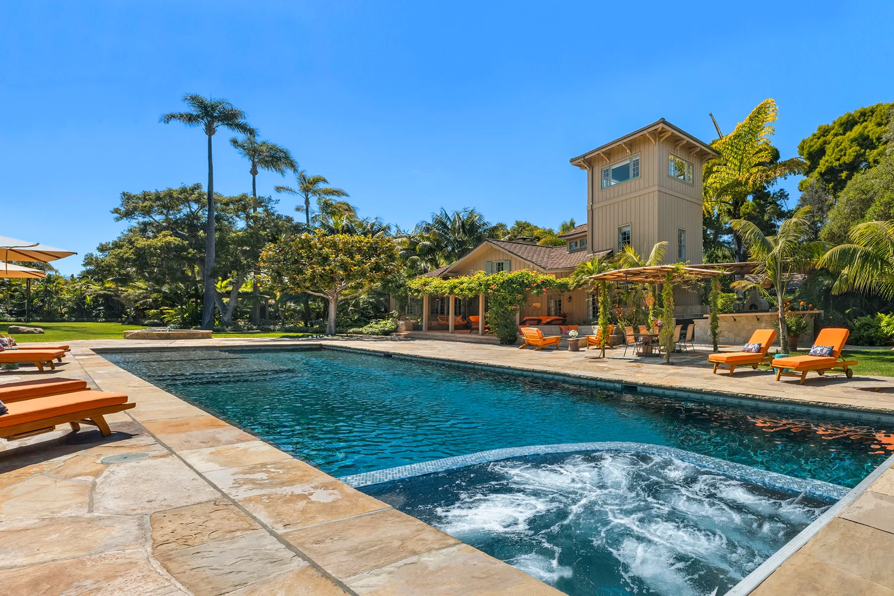 Outdoor swimming pool beside a tropical-style building, with lounge seating around the deck.