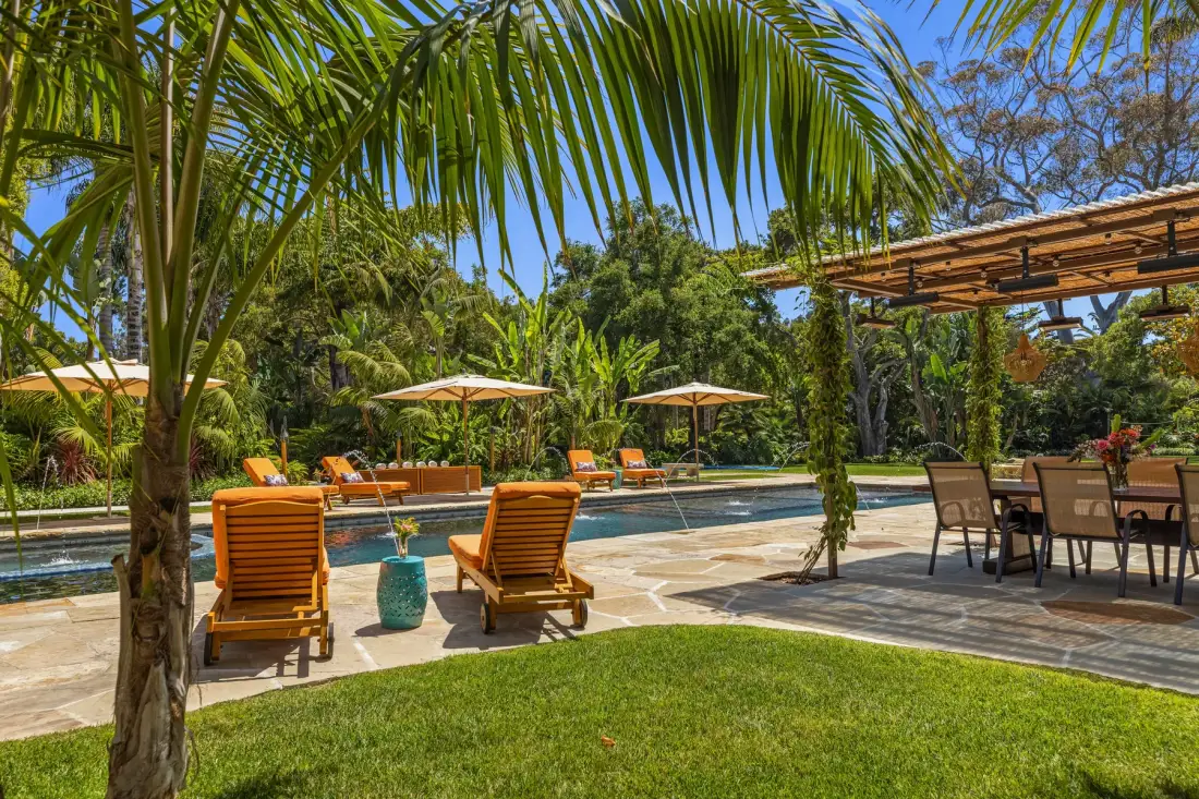 An outdoor pool area with loungers, umbrellas, and a shaded dining space.