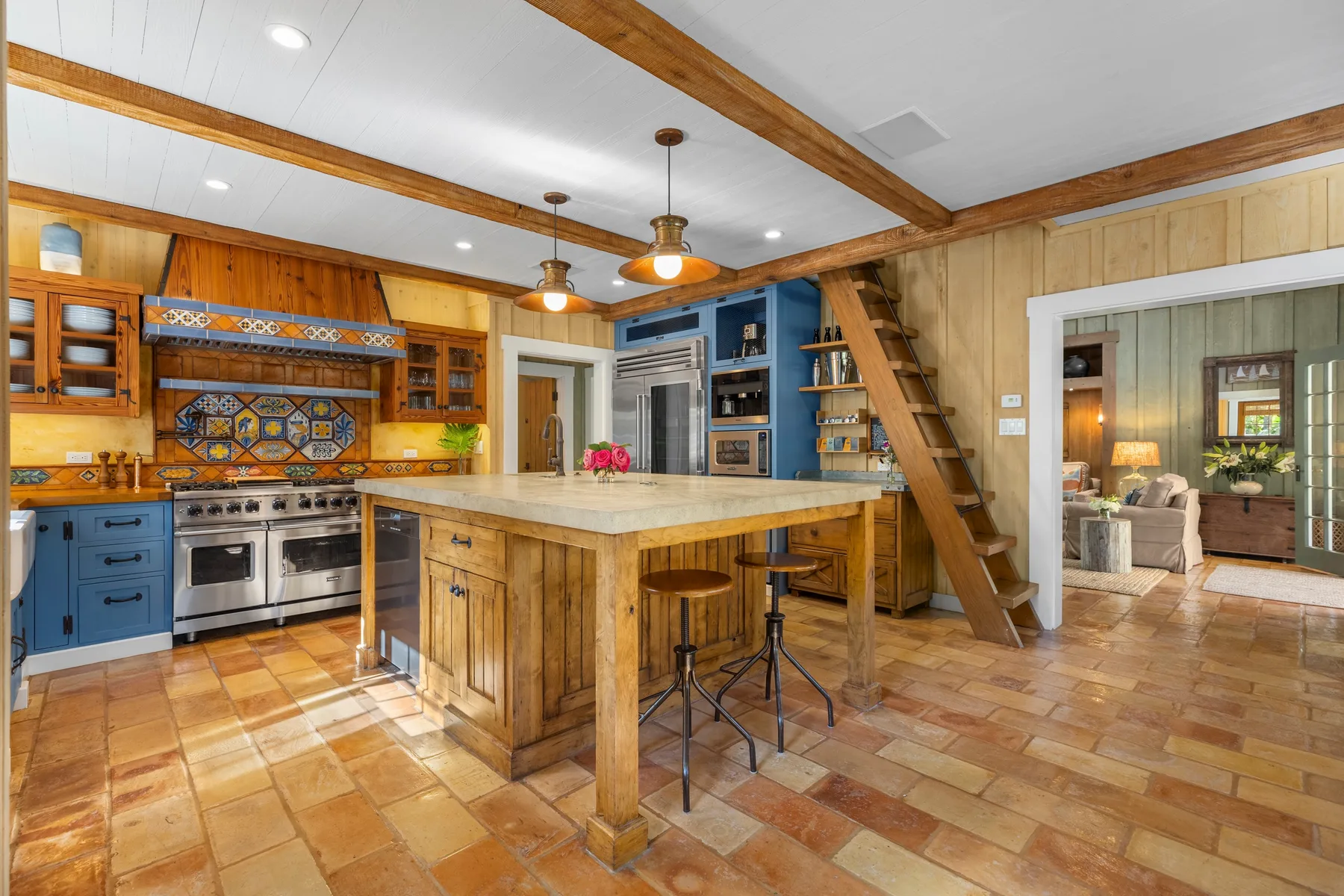 A rustic kitchen with a central island, wooden cabinetry, and tiled floors.