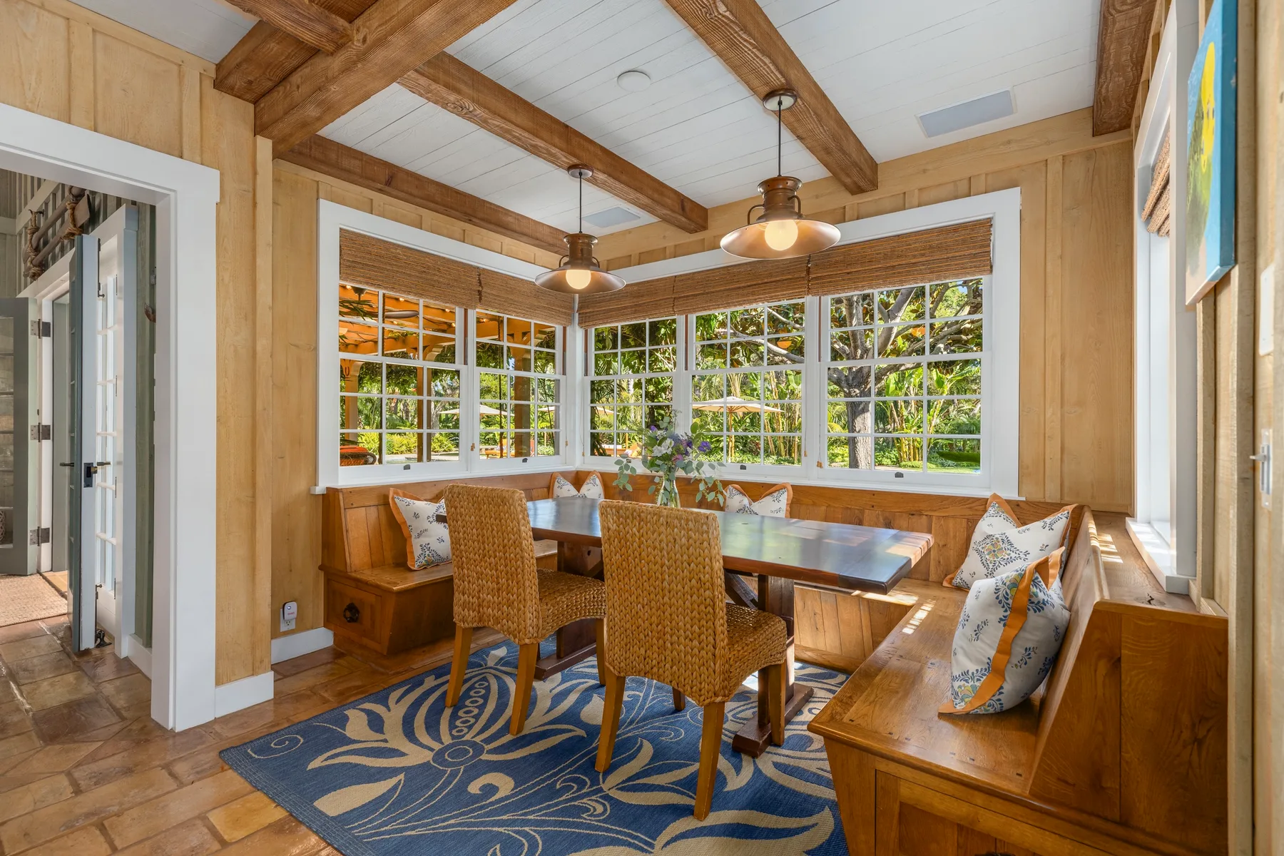A wood-paneled dining nook with a table, seating, and large windows.