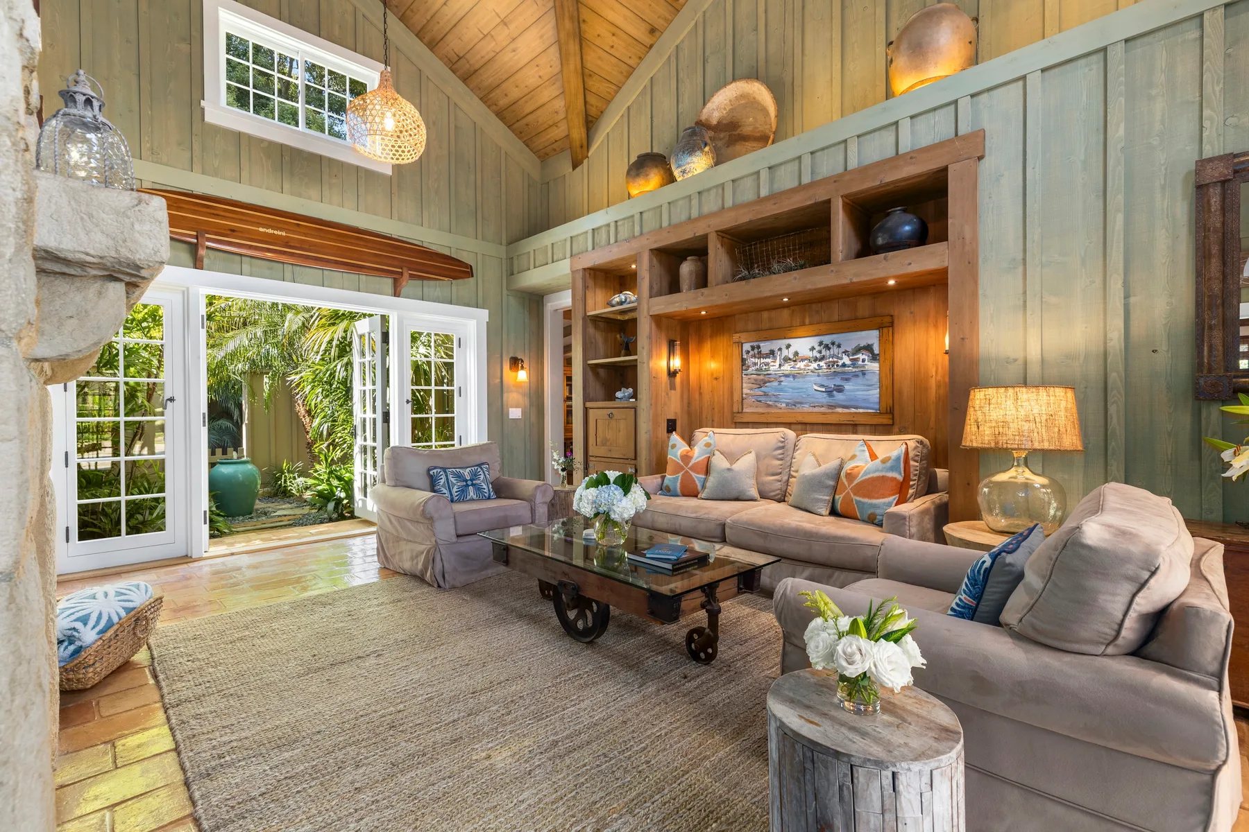 A living room with seating, a coffee table, and large open windows.