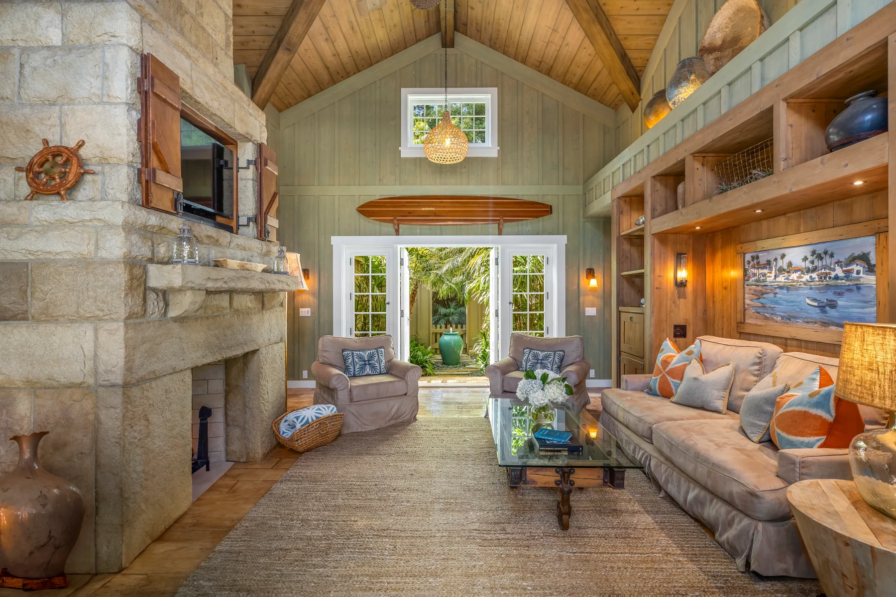 A rustic living room with a stone fireplace and seating around a coffee table.