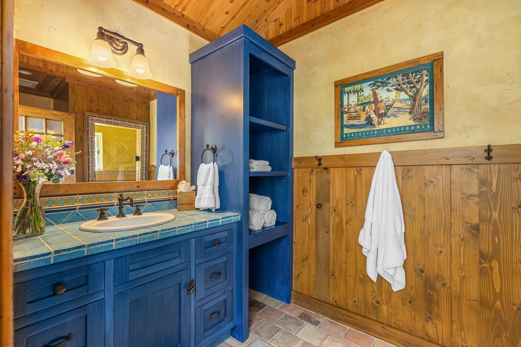 A bathroom with a blue vanity, sink, and wall-mounted towel.