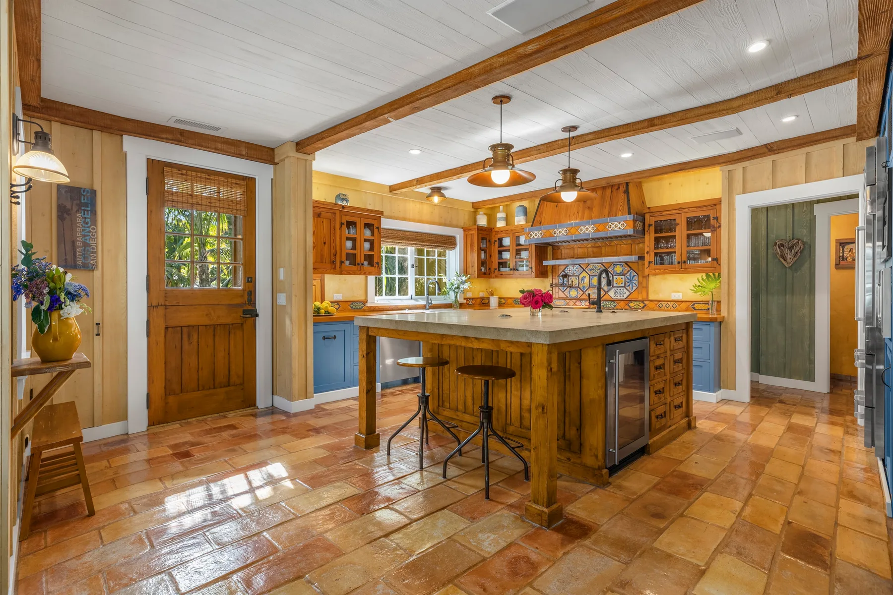A spacious kitchen with wooden cabinets, a central island, and a tiled floor.