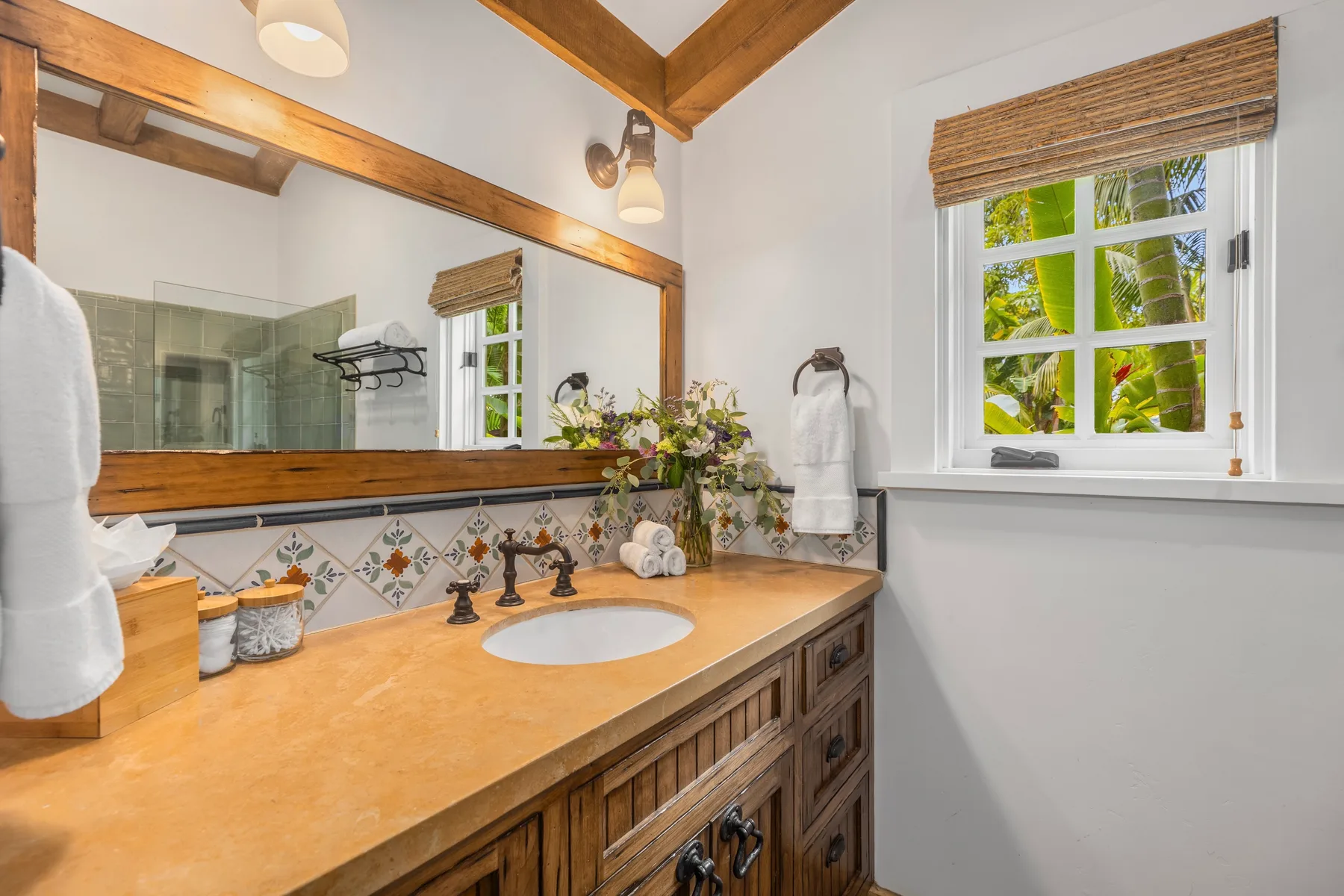 A bathroom vanity with a sink, large mirror, and window.