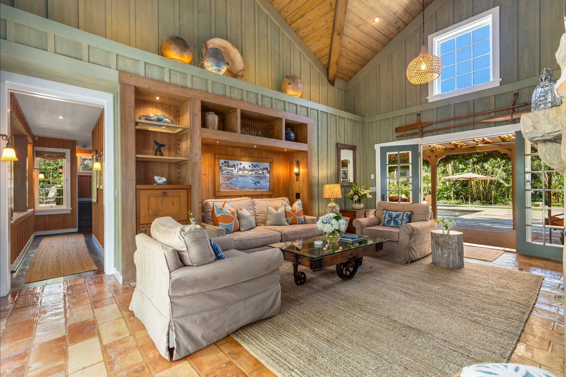 A living room with seating, a coffee table, and large windows.