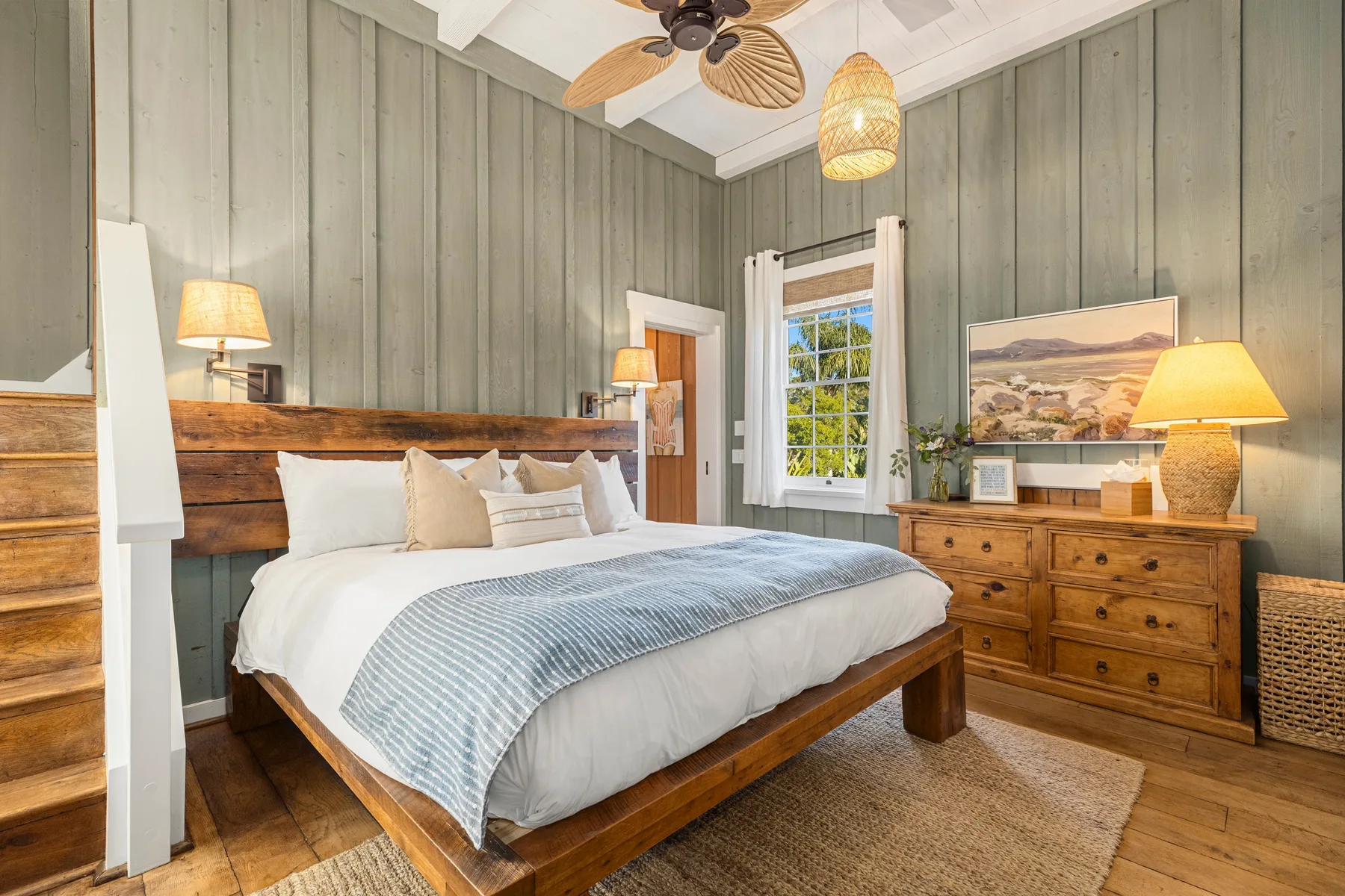 A bedroom with a wooden bed, pale bedding, and gray paneled walls.