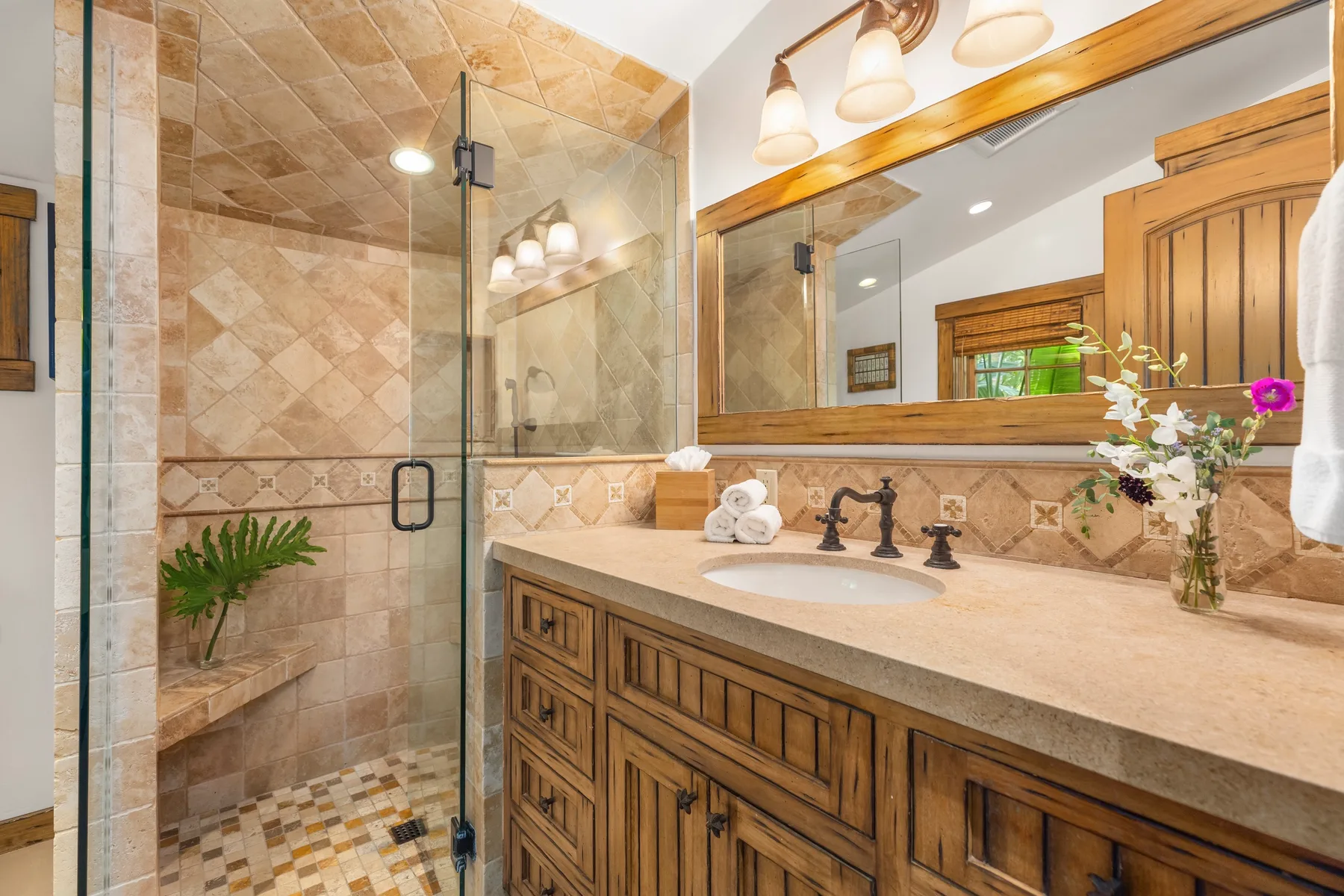 A tiled bathroom with a glass shower and a wooden vanity beneath a large mirror.