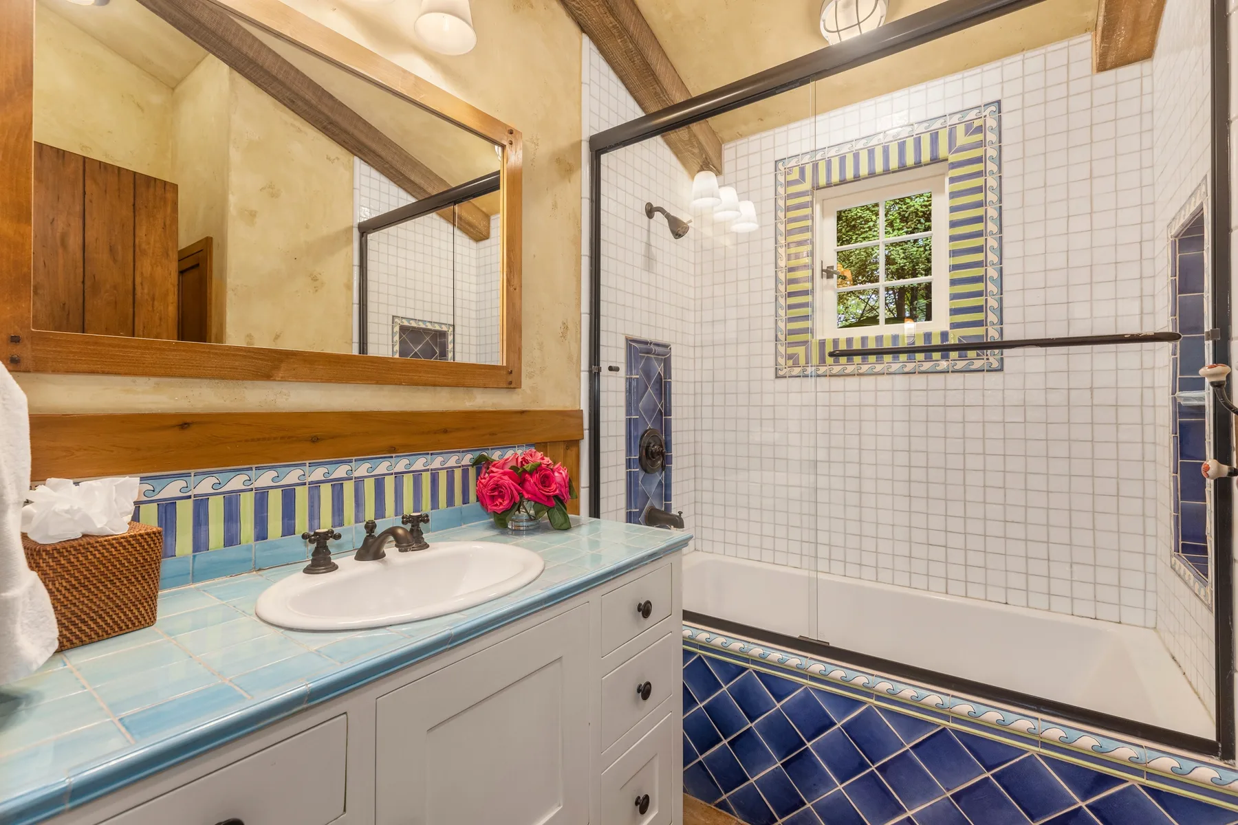 A tiled bathroom with a sink, mirror, and bathtub.