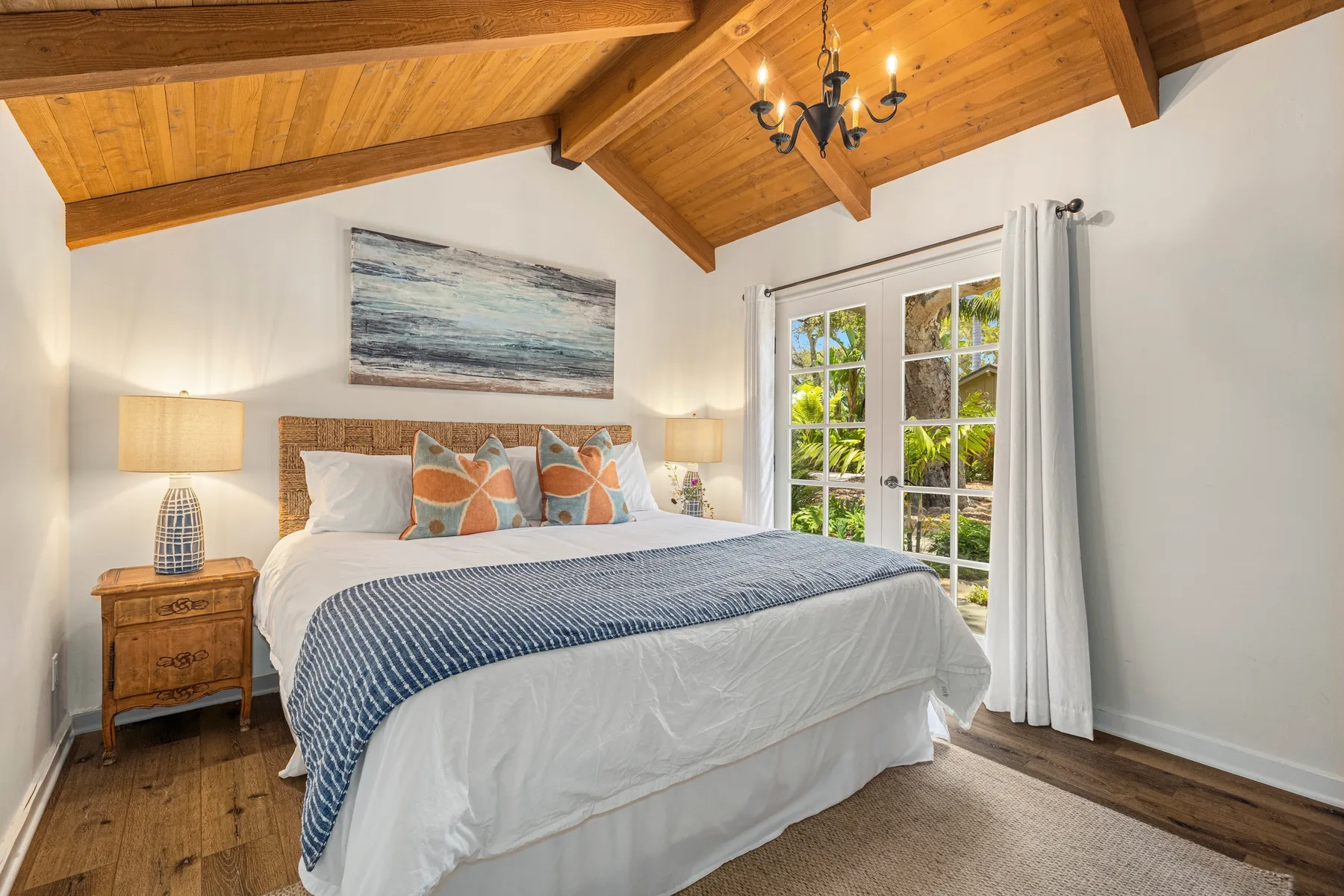A bedroom with a neatly made bed beneath a wooden ceiling.