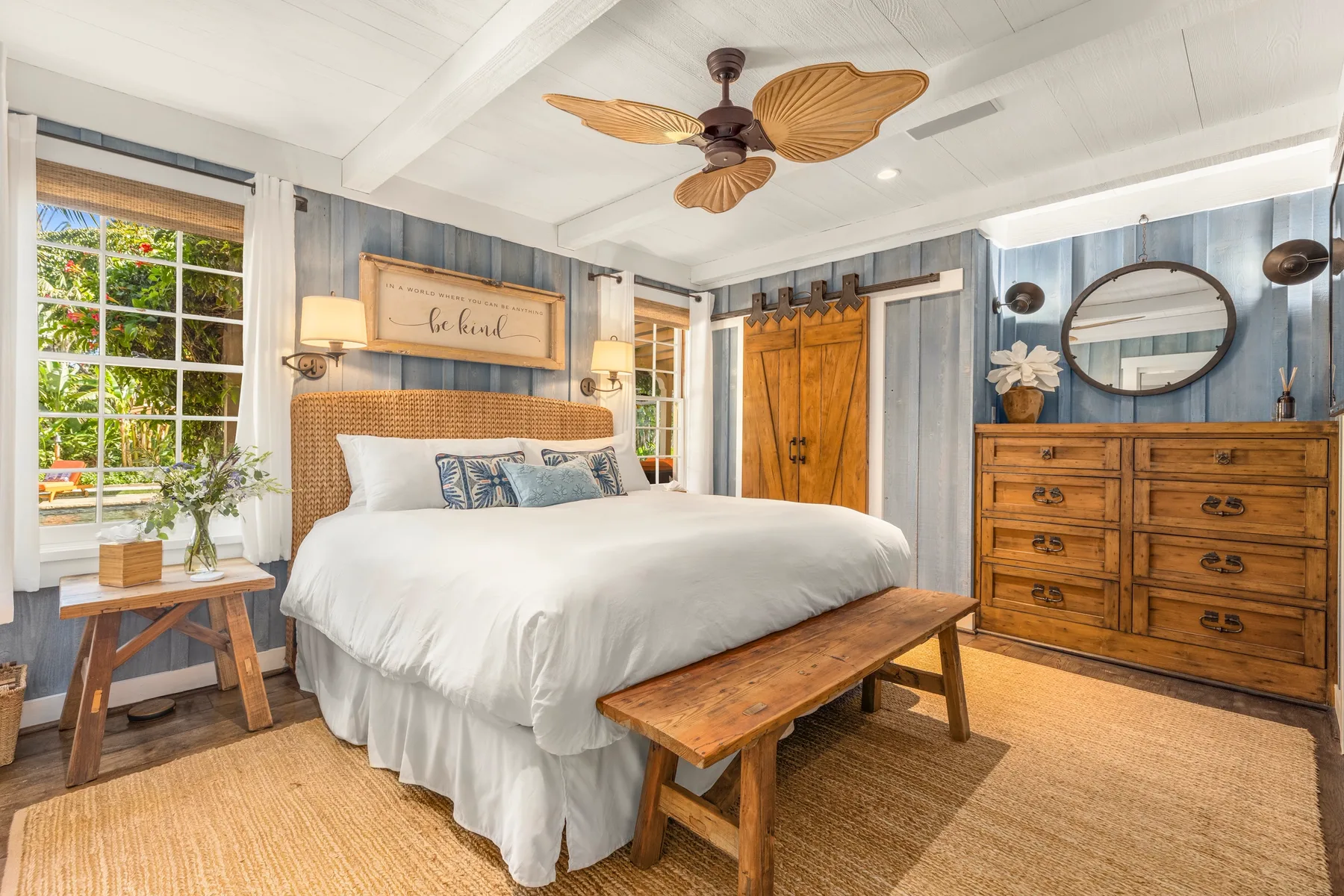 A bedroom with a large bed, wooden bench, and dresser.