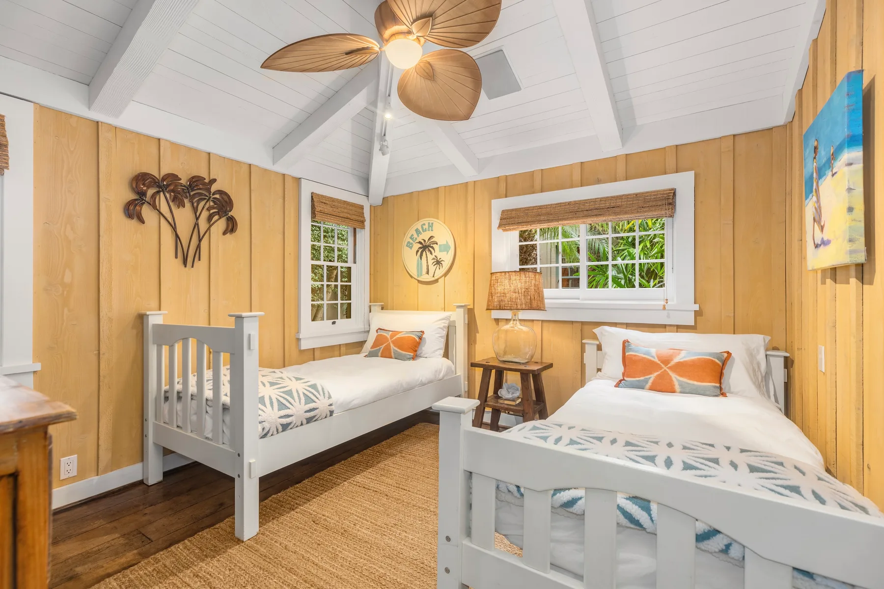 A bedroom with two beds, wood-paneled walls, and windows.