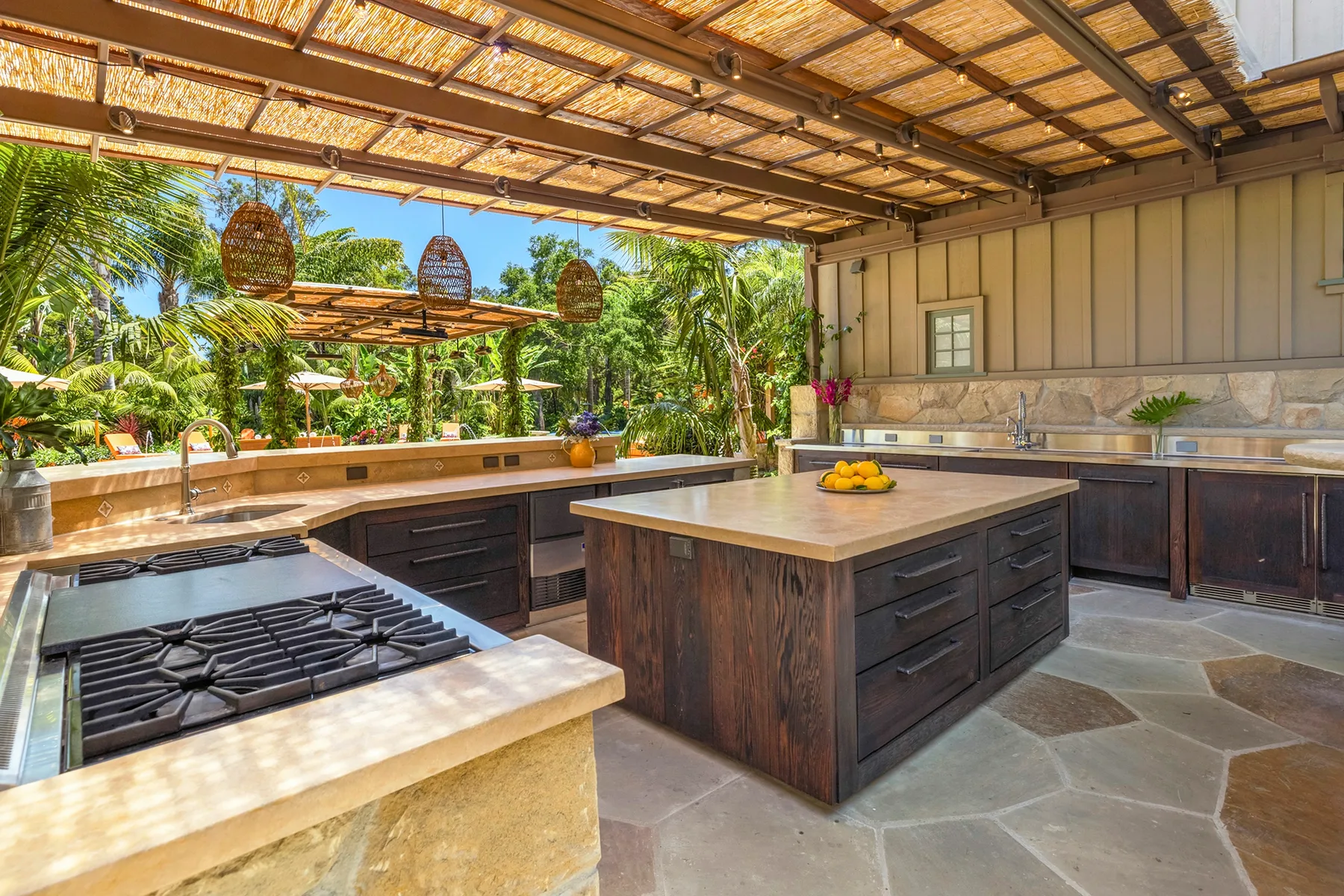 An open-air kitchen with a central island and a garden view.