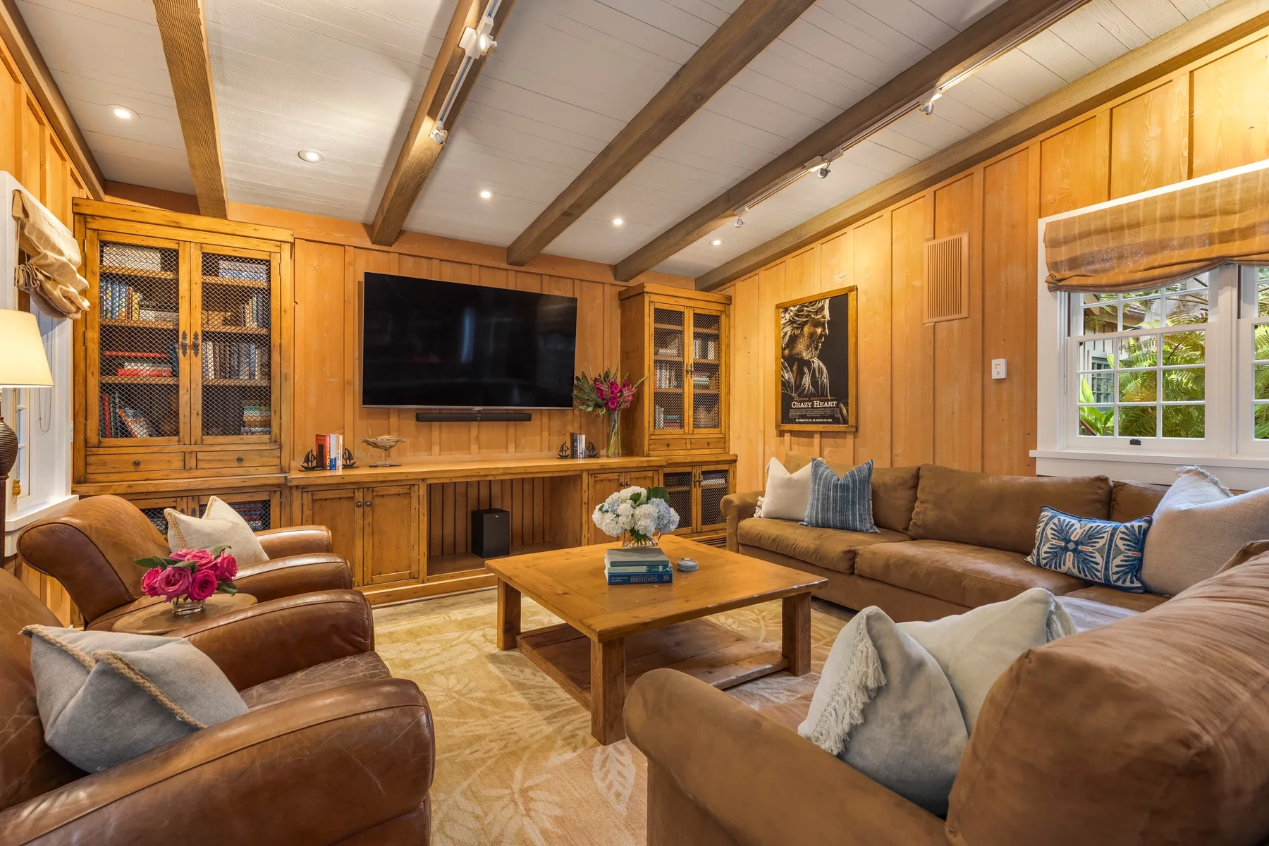 A wood-paneled living room with seating arranged around a coffee table and television.
