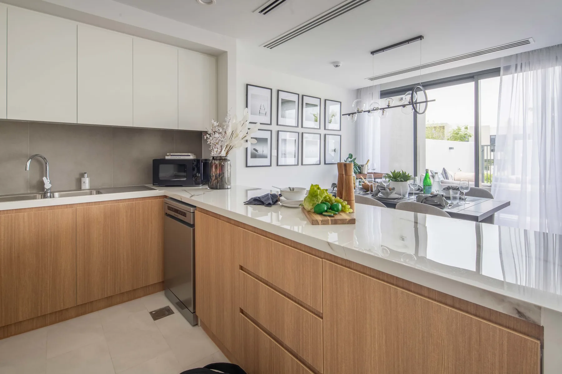 Una cocina luminosa con una barra central y un comedor junto a las ventanas.