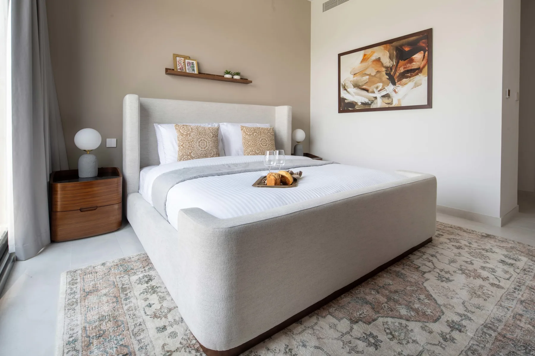 Un dormitorio luminoso con una cama bien tendida y una alfombra estampada.