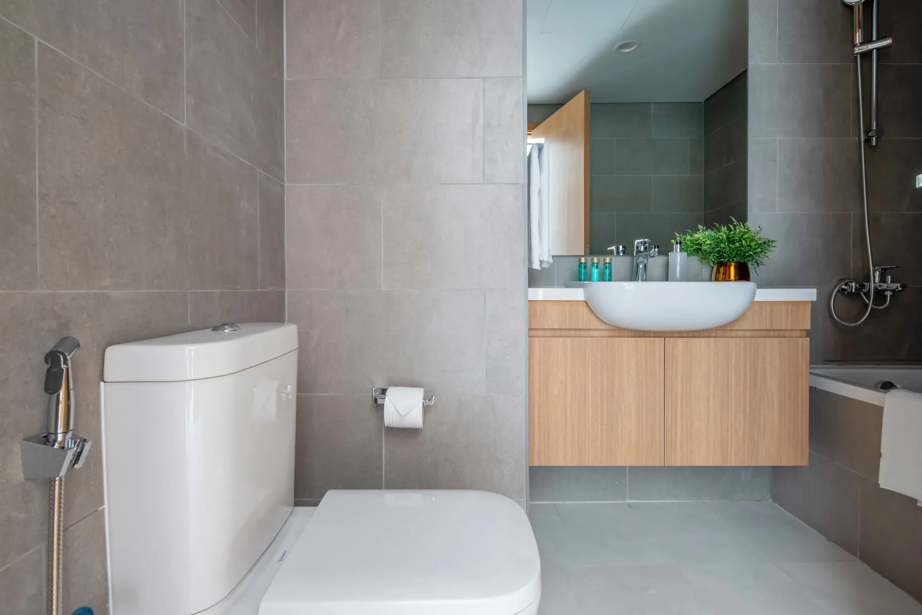 Un baño alicatado con inodoro, lavabo suspendido y bañera.