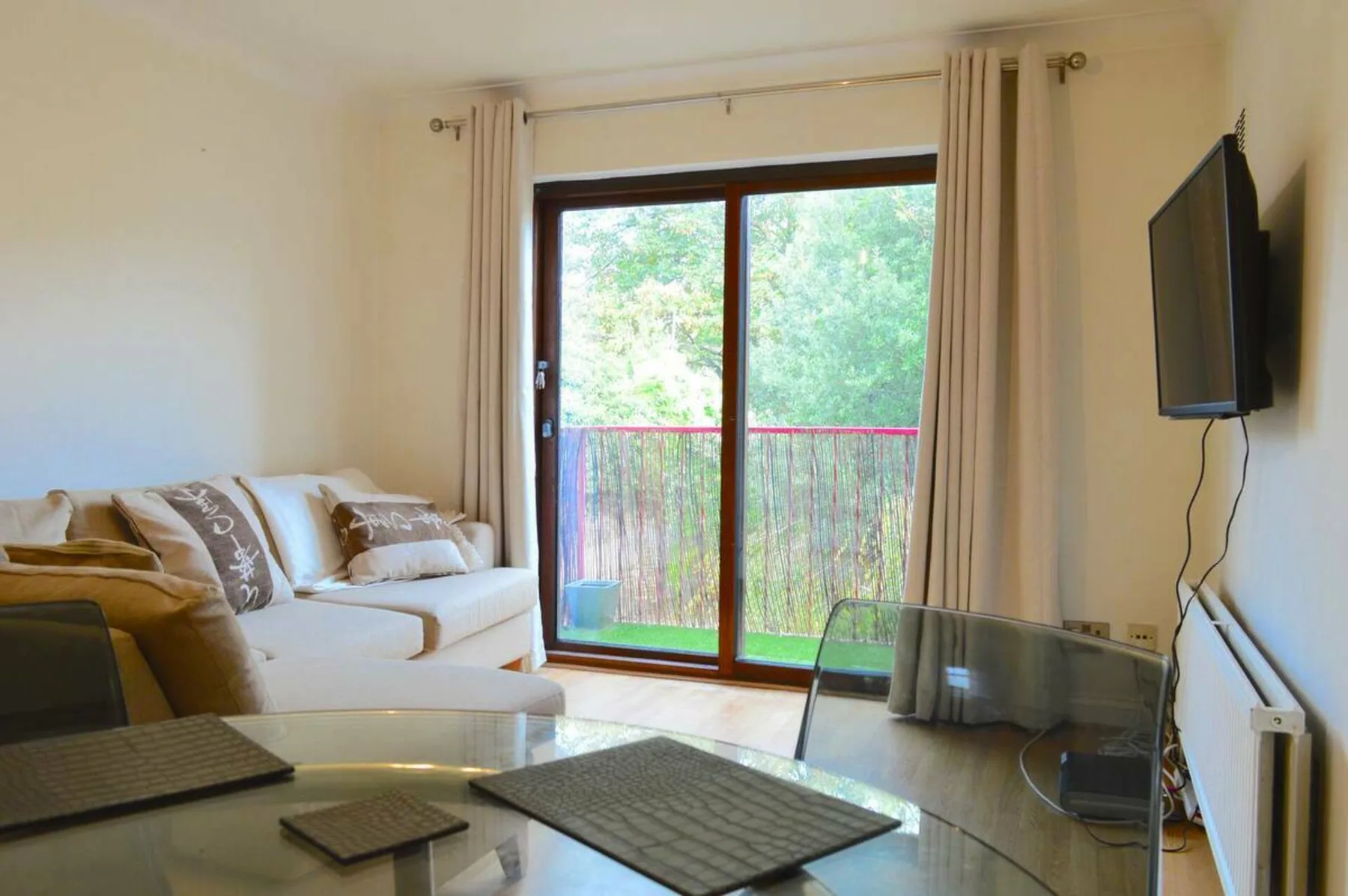 A living room with seating and a glass coffee table facing a large window.
