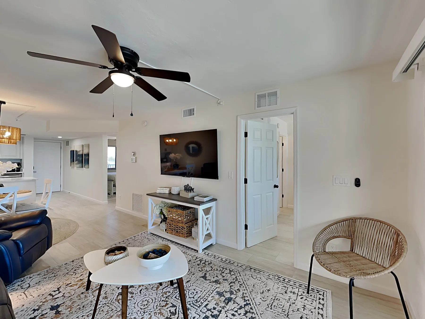 A living room with a wall-mounted television and a patterned area rug.