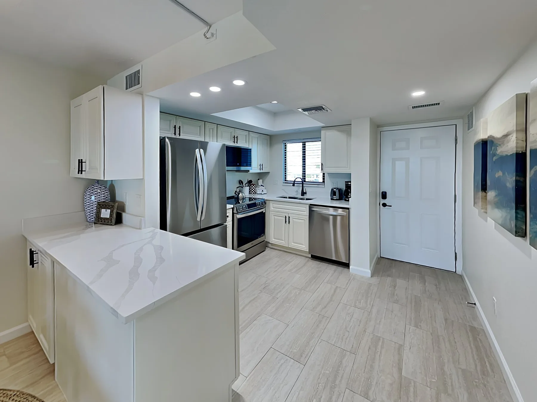 A bright kitchen with white cabinets, stainless-steel appliances, and a central island.
