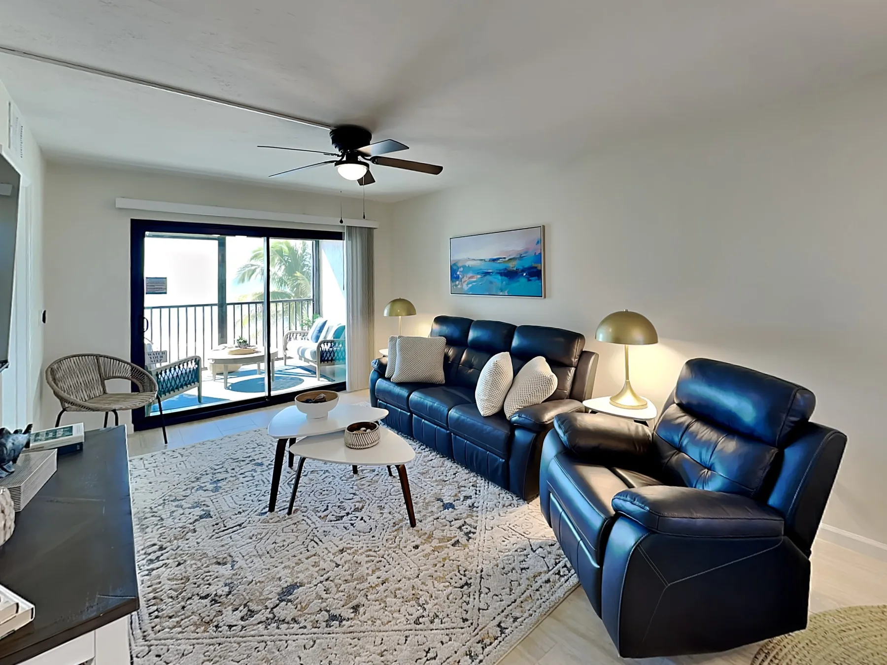 A living room with leather seating, a patterned rug, and sliding glass doors.