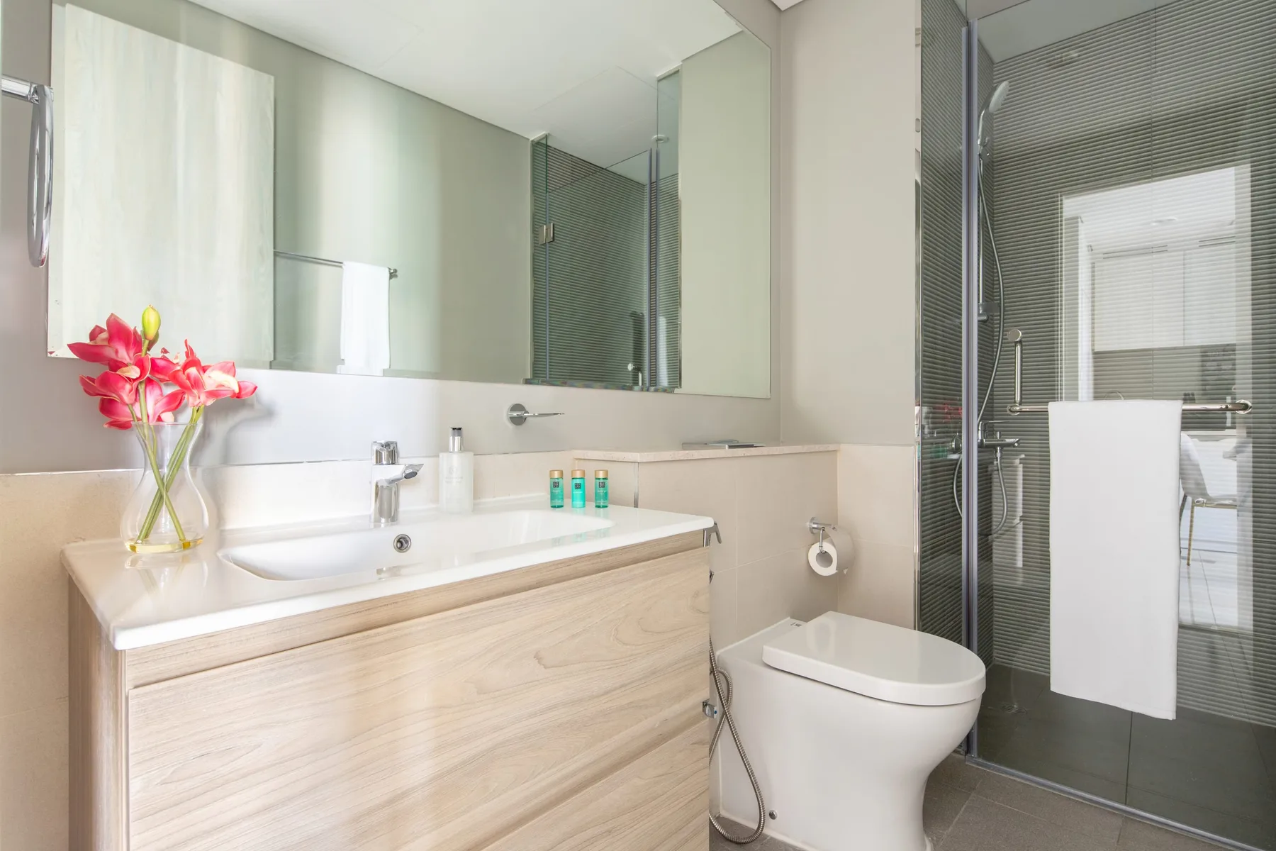 Un baño luminoso con un lavabo amplio y una ducha de vidrio.
