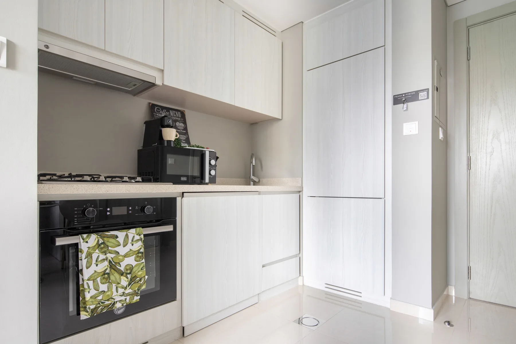 Una cocina luminosa con armarios blancos, una encimera y electrodomésticos empotrados.