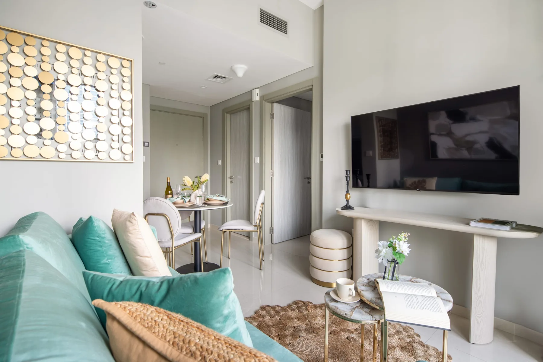 Una sala luminosa con asientos, un televisor en la pared y un pequeño comedor.