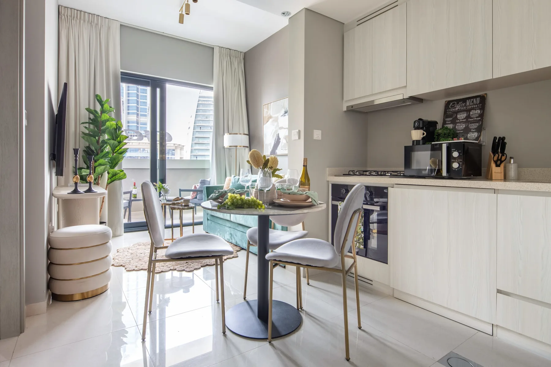 Una luminosa sala y comedor con una mesa redonda junto a una cocina compacta.